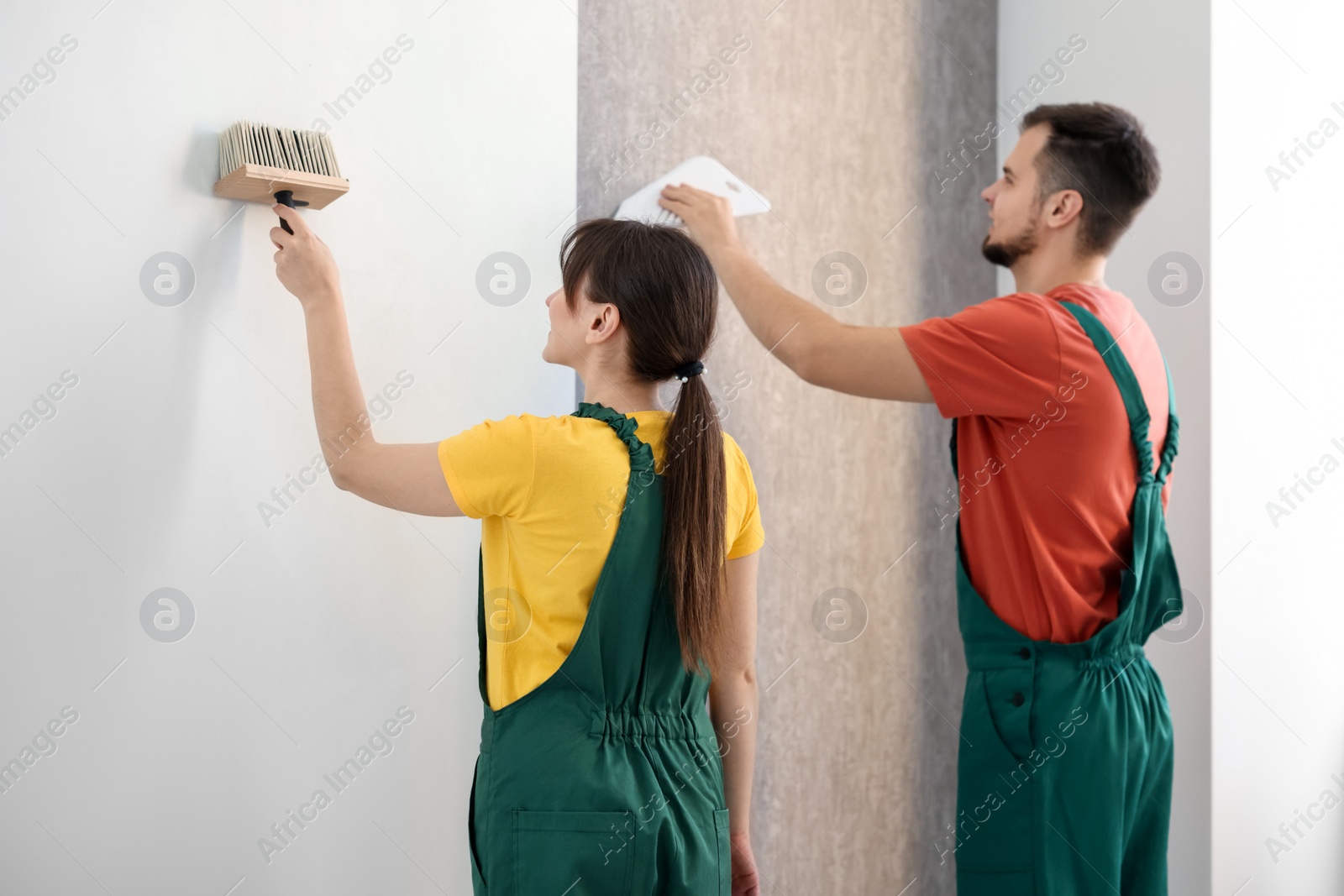 Photo of Workers hanging stylish gray wallpaper in room