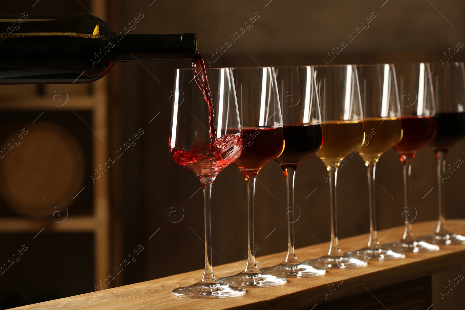 Photo of Pouring wine from bottle into glass in cellar