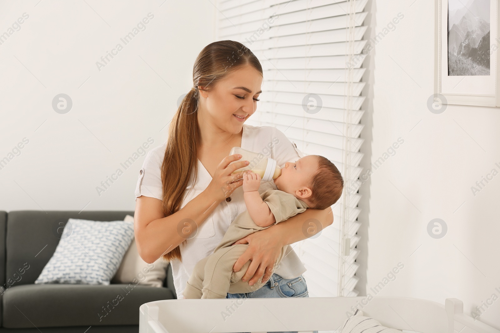 Photo of Mother feeding her cute child with infant formula indoors