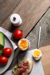 Photo of Delicious breakfast with soft boiled egg and sandwich served on wooden table, flat lay