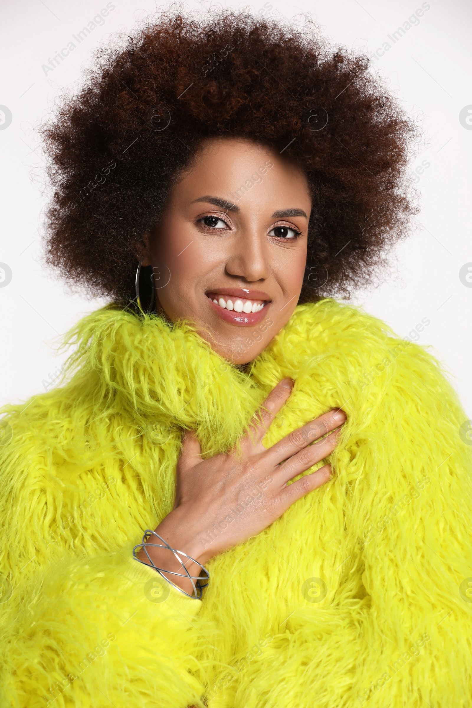 Photo of Portrait of beautiful young woman in stylish yellow fur coat on white background