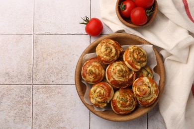 Fresh delicious puff pastry with tasty filling and tomatoes on white tiled surface, flat lay. Space for text