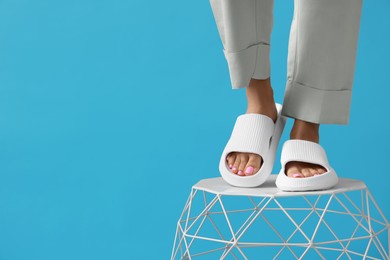 Photo of Woman wearing comfortable rubber slippers on light blue background, closeup. Space for text
