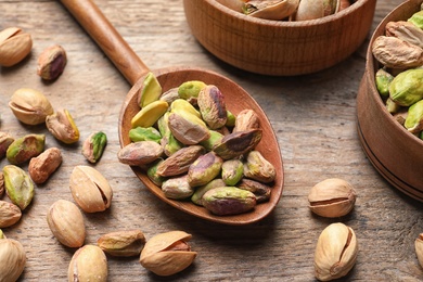 Photo of Composition with organic pistachio nuts on wooden table, closeup