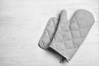 Oven glove and potholder on white wooden background, flat lay. Space for text