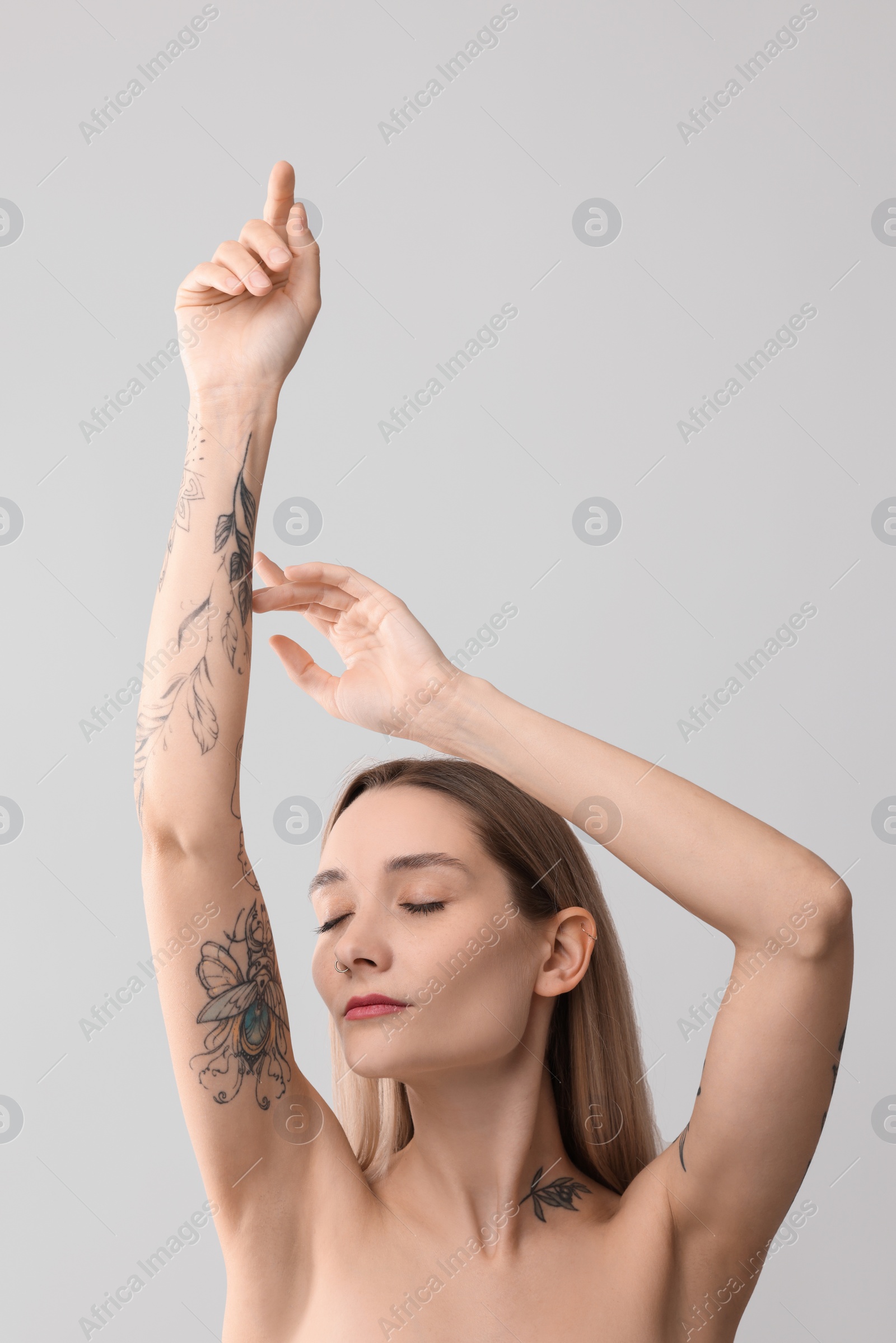 Photo of Portrait of beautiful tattooed woman on light background