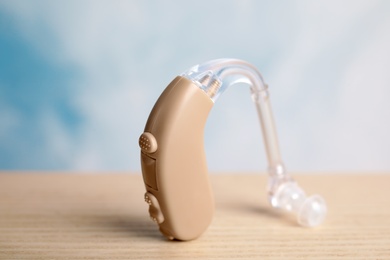 Photo of Hearing aid on wooden table, closeup. Medical device