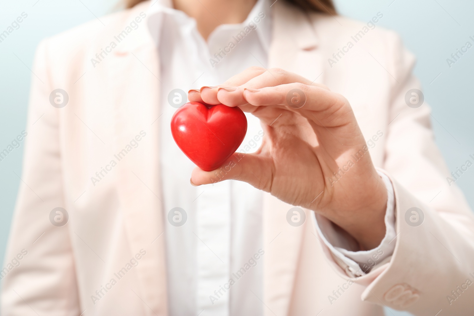 Photo of Woman holding small red heart on light background, closeup. Heart attack concept