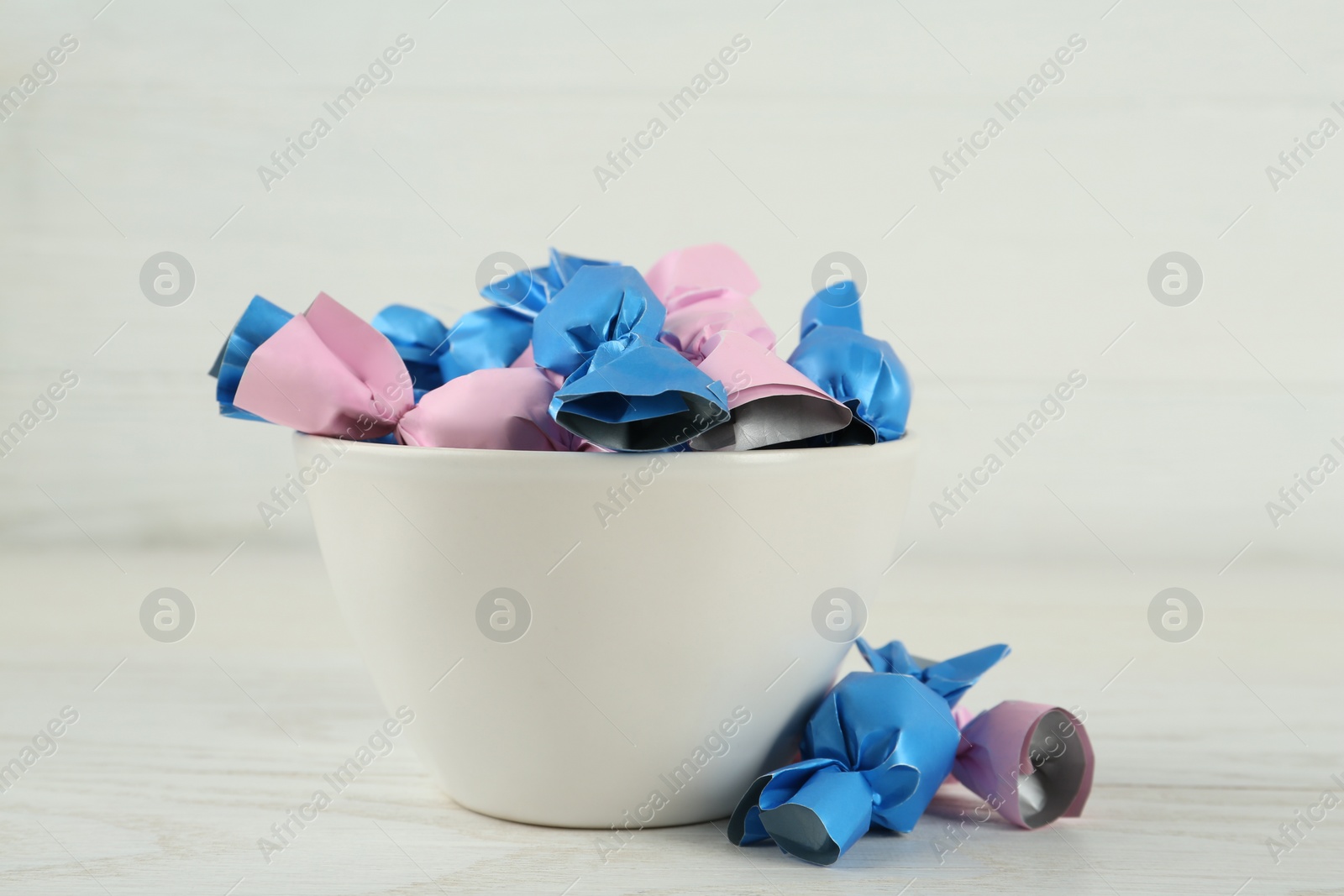 Photo of Candies in colorful wrappers on white wooden table, closeup