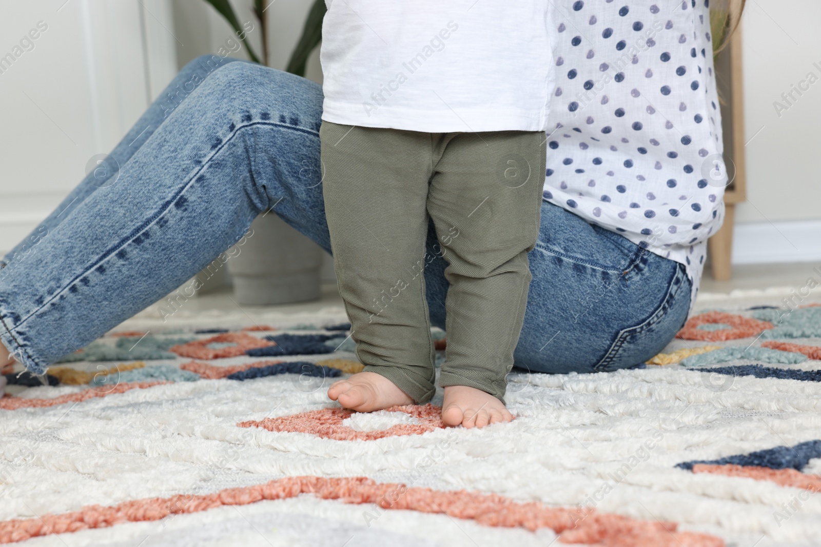 Photo of Mother with her son on soft carpet indoors, closeup