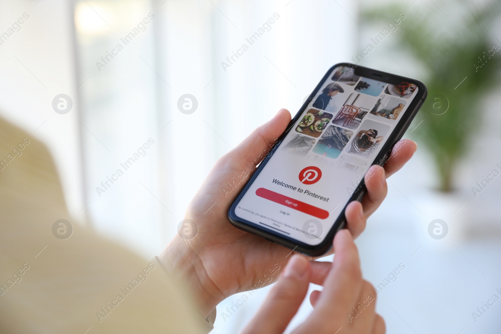 Photo of MYKOLAIV, UKRAINE - MARCH 16, 2020: Woman holding iPhone 11 with Pinterest app on screen indoors, closeup