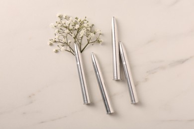Photo of Bullets and beautiful gypsophila flowers on light marble table, flat lay