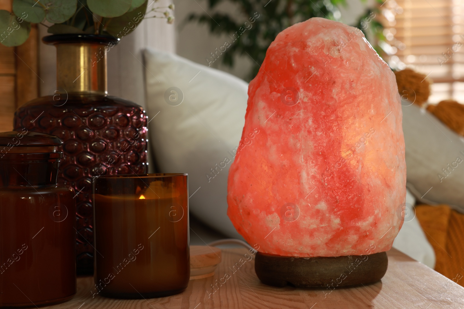 Photo of Beautiful Himalayan salt lamp on wooden nightstand in bedroom