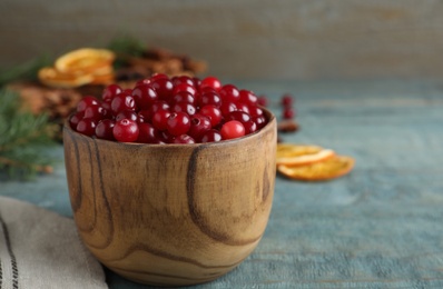 Photo of Fresh ripe cranberries on blue wooden table. Space for text