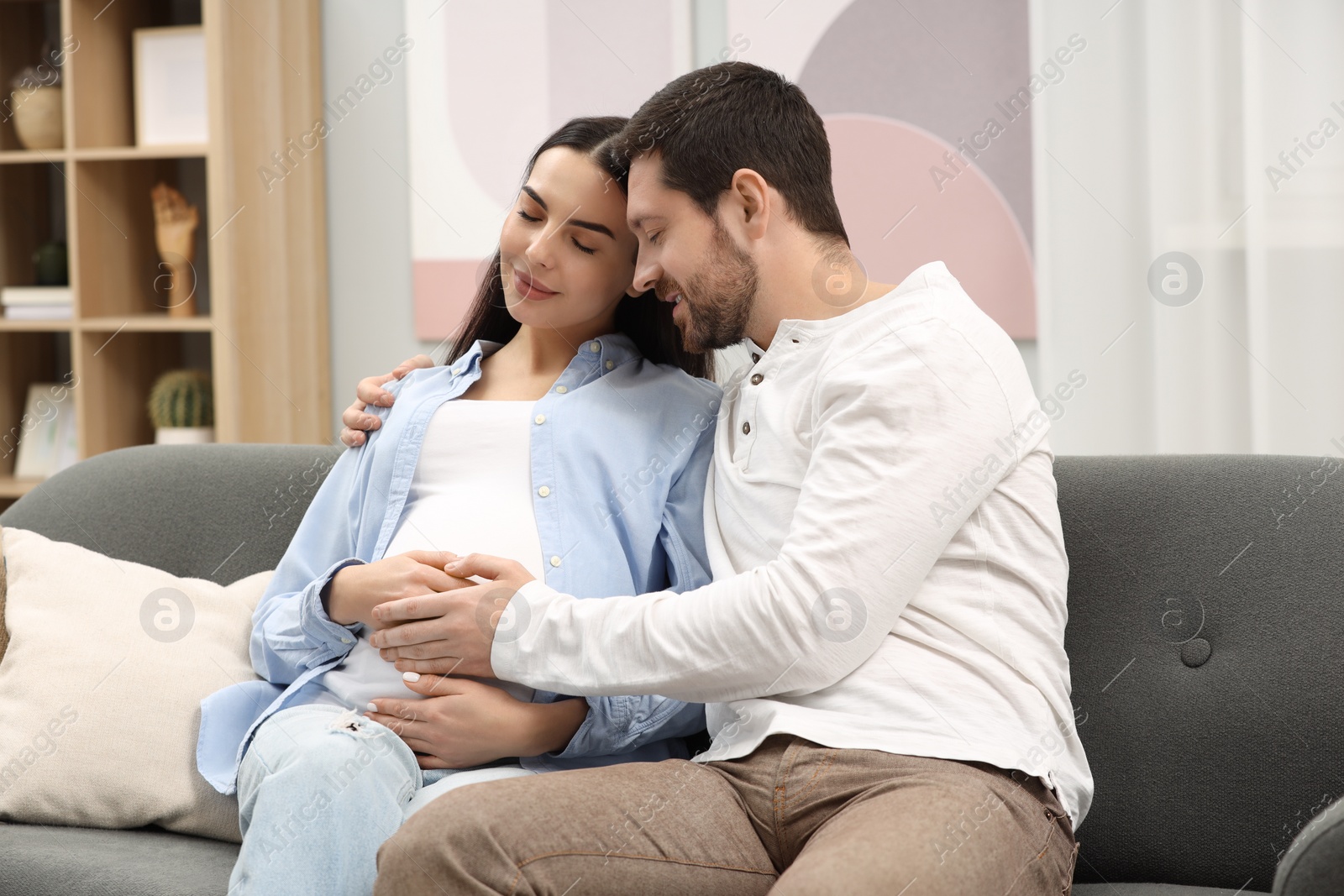 Photo of Pregnant woman with her husband on sofa at home