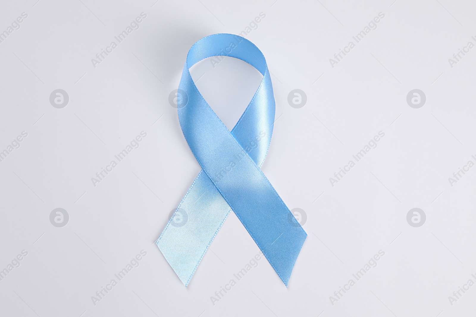 Photo of International Psoriasis Day. Light blue ribbon as symbol of support on white background, top view