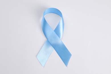 International Psoriasis Day. Light blue ribbon as symbol of support on white background, top view