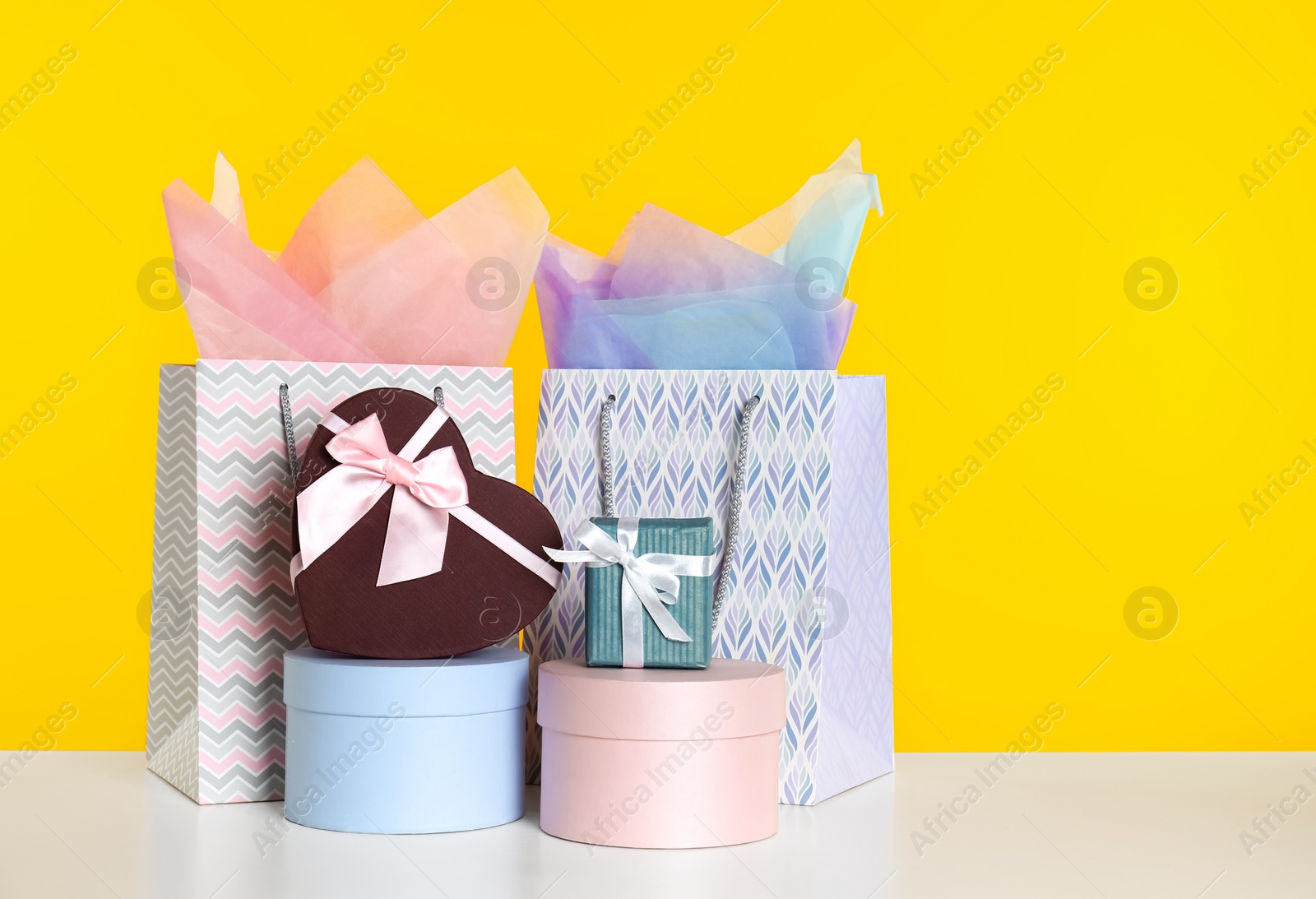 Photo of Shopping bags and gift boxes on yellow background