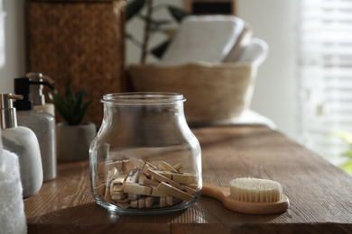 Photo of Jar with clothespins and shower brush on shelf indoors. Bathroom interior elements