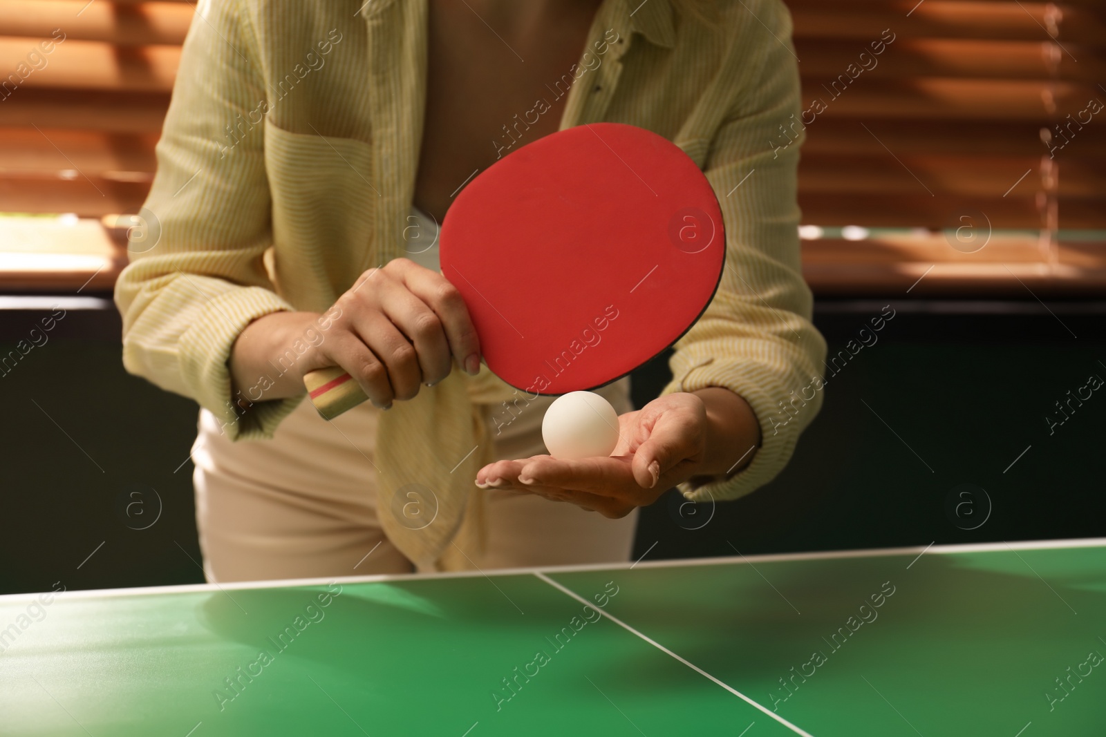 Photo of Woman playing ping pong indoors, closeup view