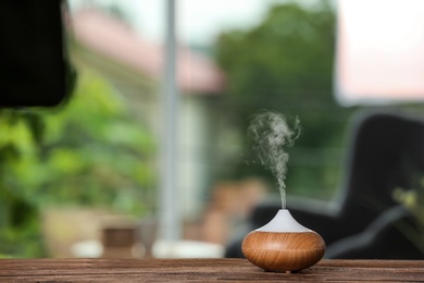 Aroma oil diffuser lamp on table against blurred background