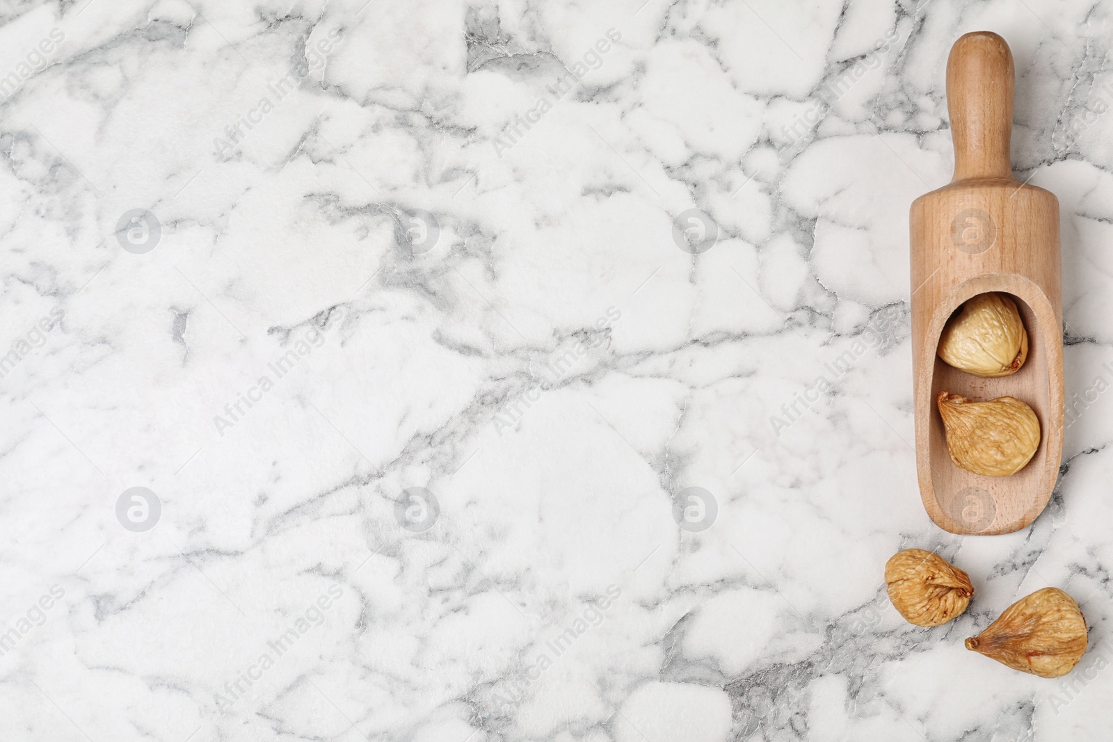 Photo of Scoop of dried figs on marble table, top view with space for text. Healthy fruit