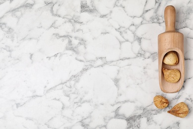 Photo of Scoop of dried figs on marble table, top view with space for text. Healthy fruit