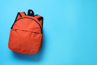 Photo of Stylish orange backpack on light blue background, top view. Space for text