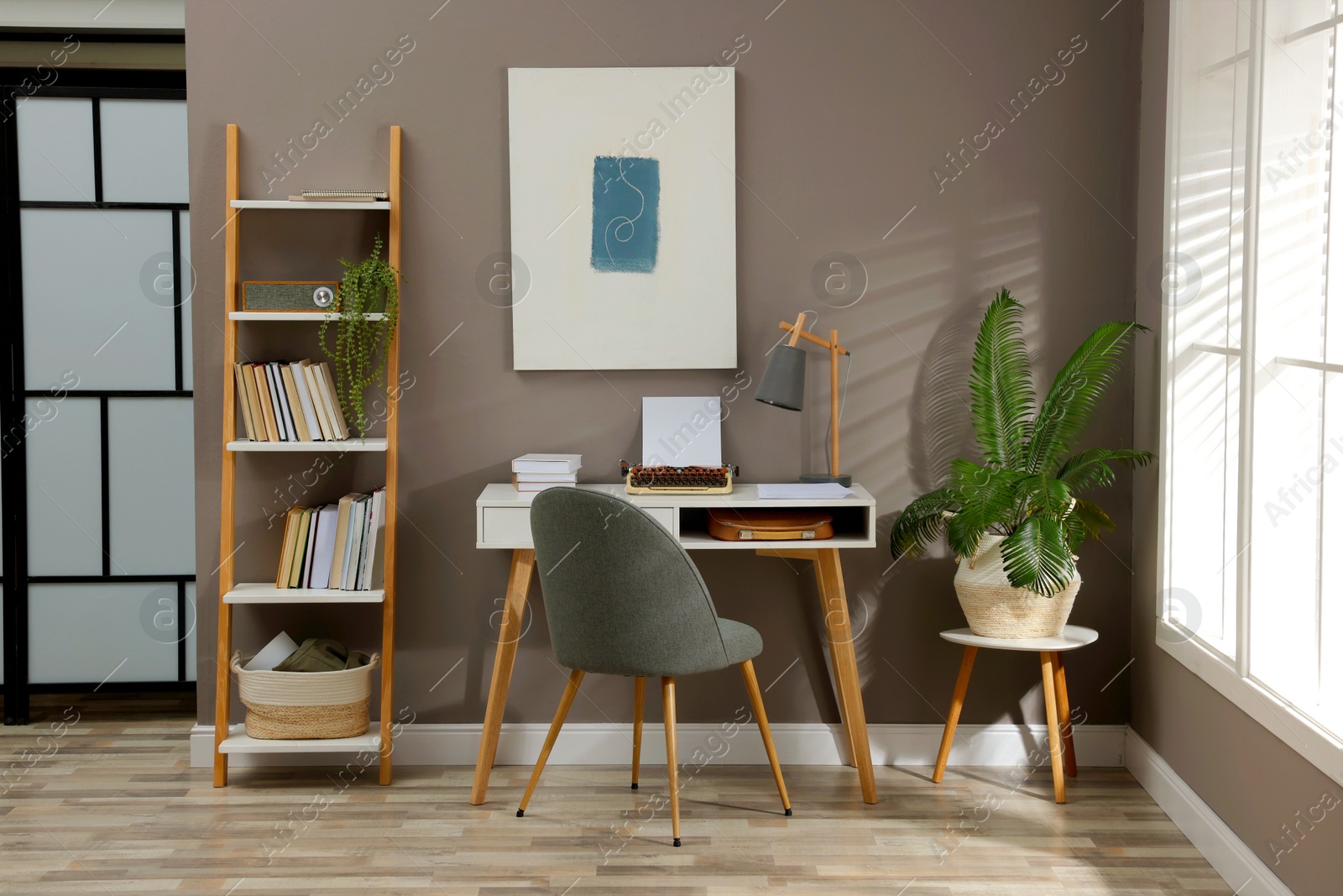 Photo of Comfortable writer's workplace interior with typewriter on desk near grey wall