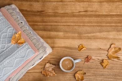 Photo of Flat lay composition with warm autumn clothes and space for text on wooden background