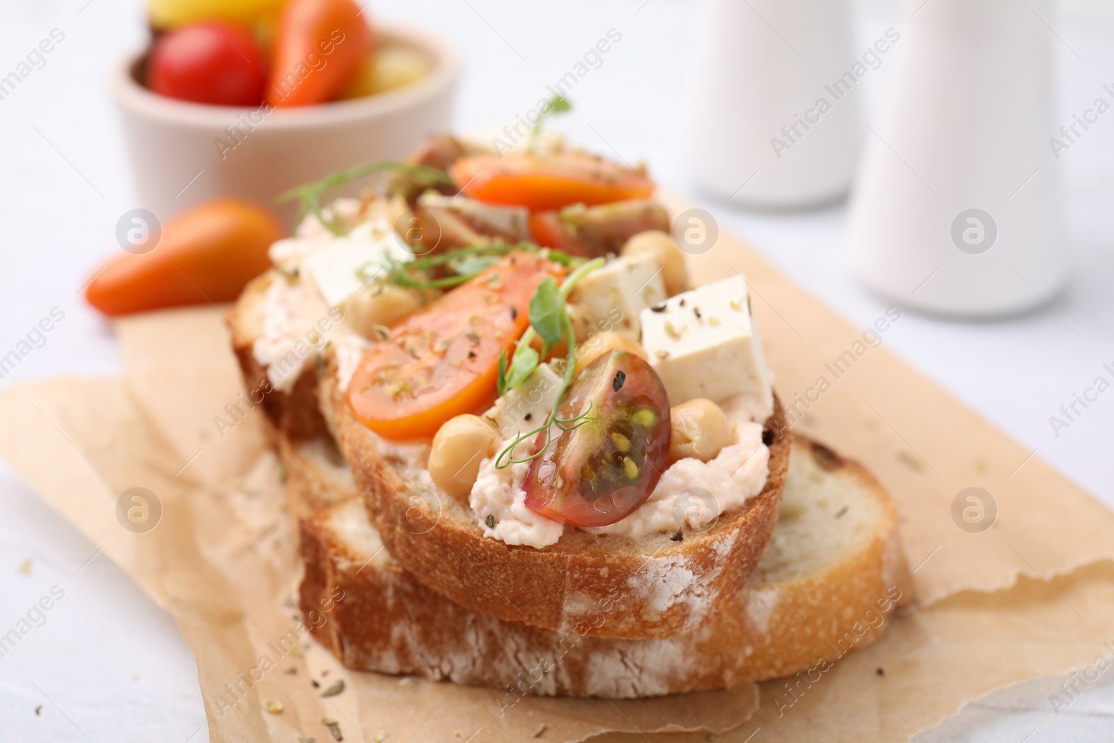 Photo of Tasty vegan sandwich with tomatoes, tofu and chickpeas on white table, closeup