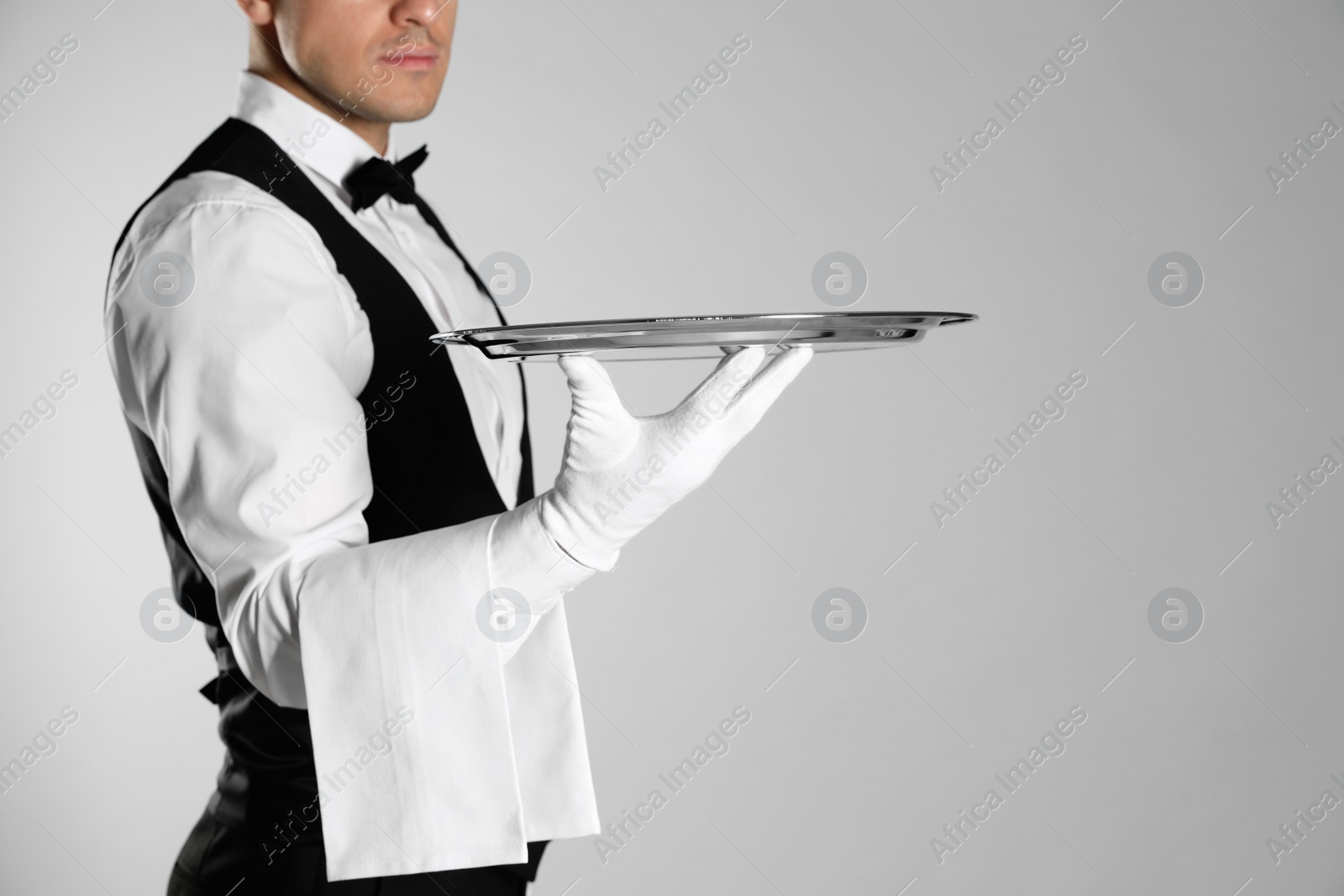 Photo of Butler with tray on light grey background, closeup. Space for text