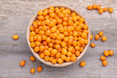 Bowl with fresh ripe sea buckthorn berries on wooden table, flat lay