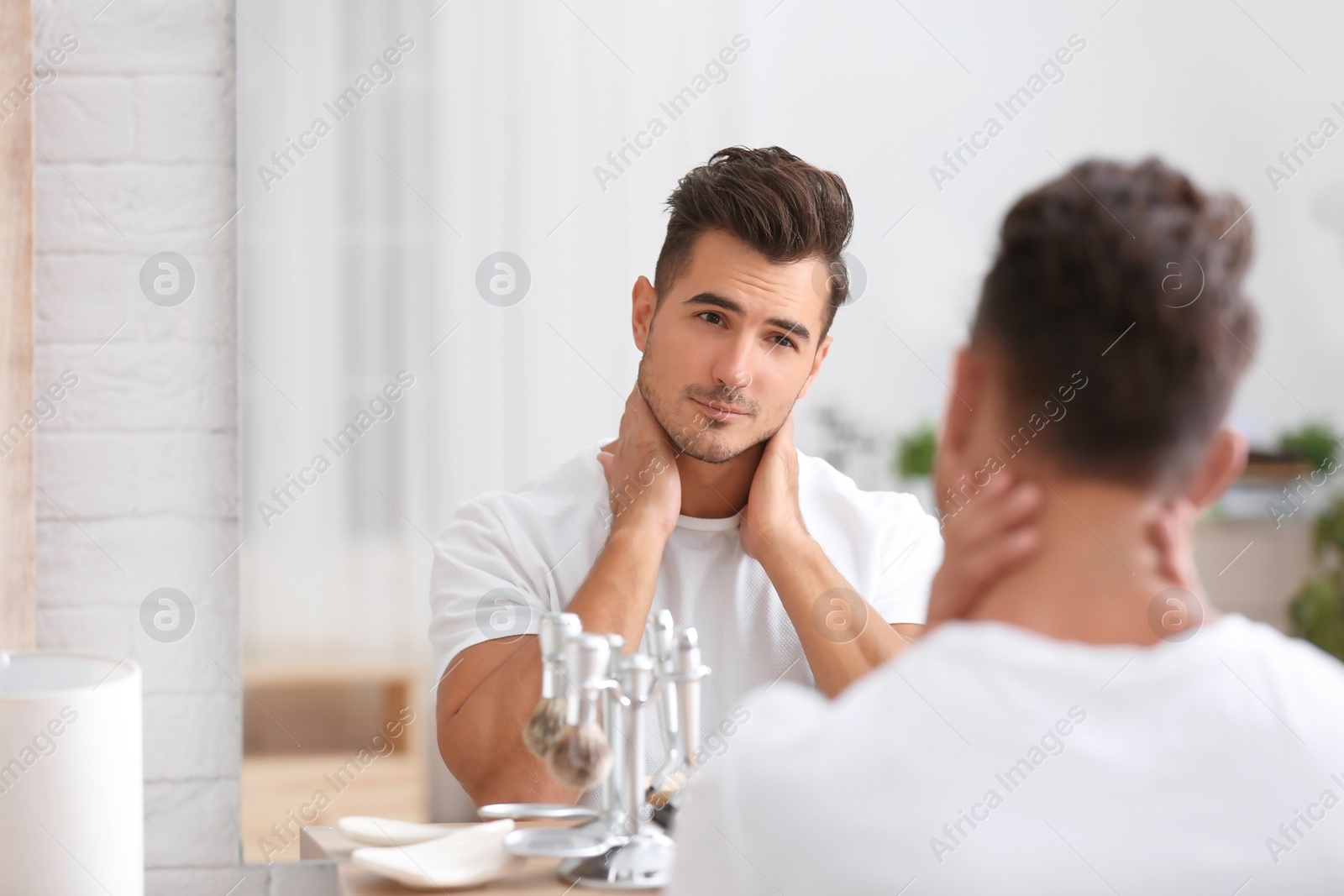 Photo of Young man with stubble ready for shaving near mirror in bathroom