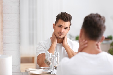 Young man with stubble ready for shaving near mirror in bathroom