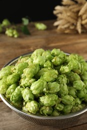 Fresh green hops in sieve on wooden table, closeup