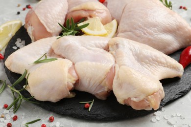 Photo of Fresh raw chicken meat and other products on slate board, closeup