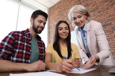 Photo of Female notary working with young couple in office