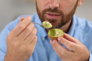 Photo of Man eating fresh kiwi with spoon, closeup
