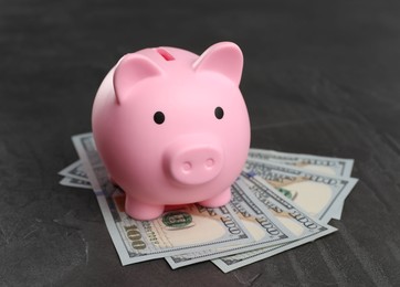 Pink piggy bank and banknotes on black table