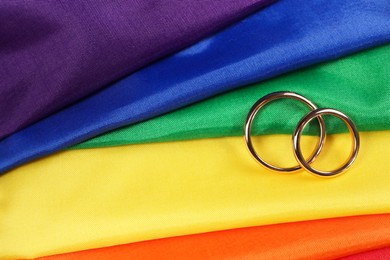 Wedding rings on rainbow LGBT flag, top view