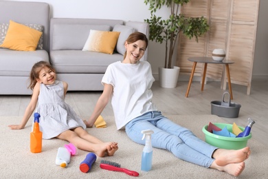 Housewife and daughter resting after cleaning in room