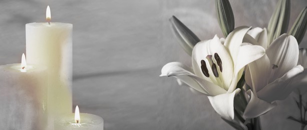 Image of Funeral. White lilies and burning candles on light grey background, banner design