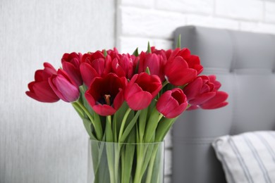 Photo of Glass vase with bouquet of beautiful tulips in bedroom