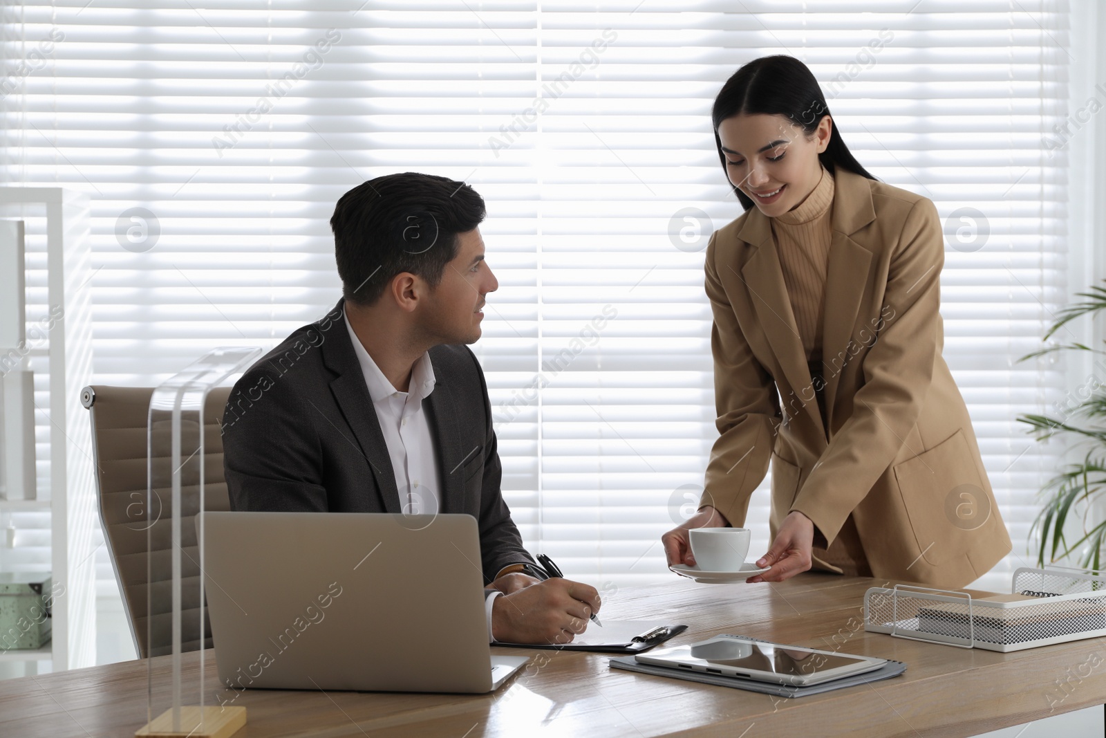 Photo of Secretary bringing coffee to her boss in office