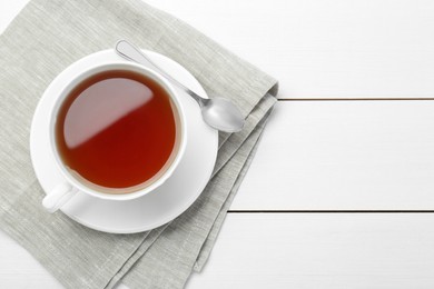 Aromatic tea in cup and spoon on white wooden table, top view. Space for text