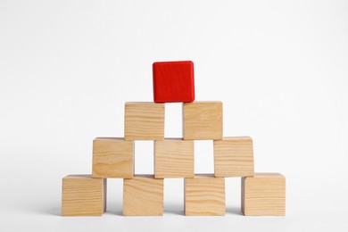 Blank wooden cubes and red one stacked on white background