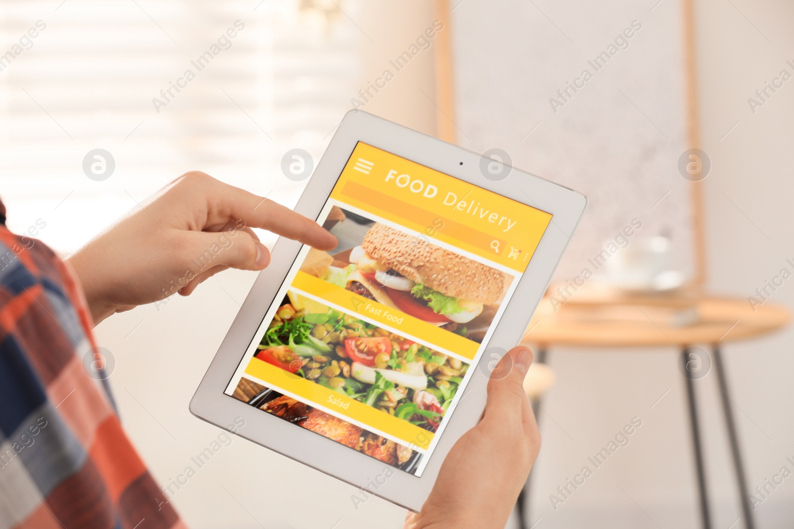 Photo of Man using tablet for ordering food online at home, closeup. Concept of delivery service