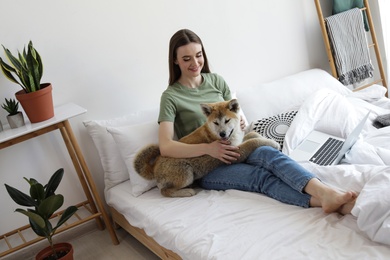 Photo of Young woman and Akita Inu dog in bedroom decorated with houseplants