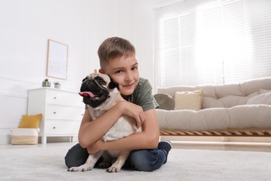 Photo of Boy hugging his cute pug in living room. Space for text